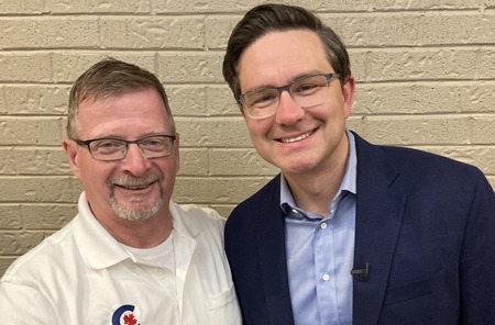 Stephen gallant smiling while shaking hands with smiling Pierre Poilievre