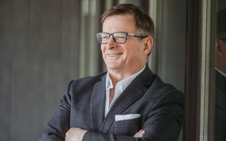 Stephen Gallant smiling in a suit with arms crossed